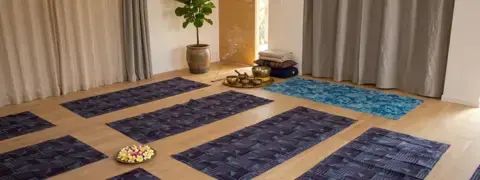 Salle de pratique de 32 m² avec parquet en chêne clair, baignée de lumière naturelle, prête pour un stage de yoga ou de méditation à l'Espace Ker Gana.