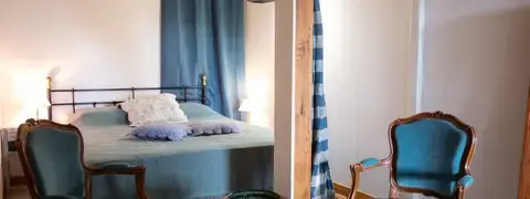 Chambre du Domaine de La Planésié avec salle d'eau privée, lumière douce et poutres apparentes
