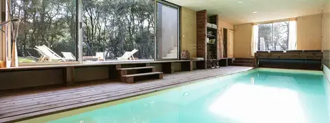 La piscine intérieure chauffée de la Villa Cayola, ouverte sur l'extérieur pour un bain avec vue sur la nature environnante.